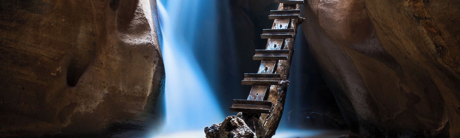 Una escalera de madera que desciende hacia un cañón con una cascada.