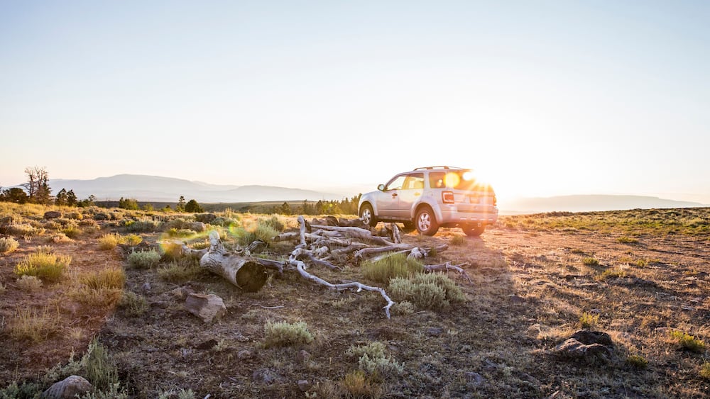 SUV car at sunrise in natural setting, Koosharem, Utah, USA