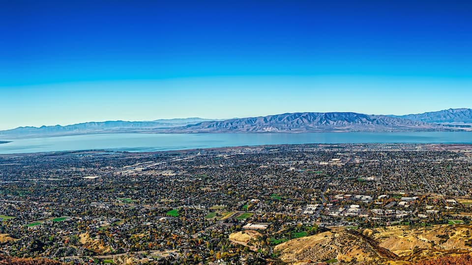 A panoramic view of a city with a large body of water and mountains in the background.
