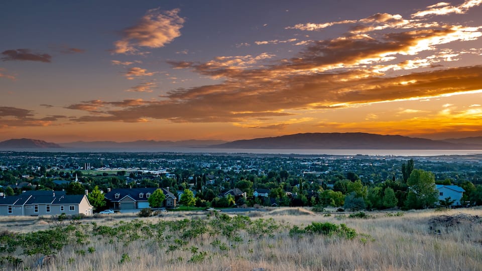 A sunset over a coastal city with mountains in the background.