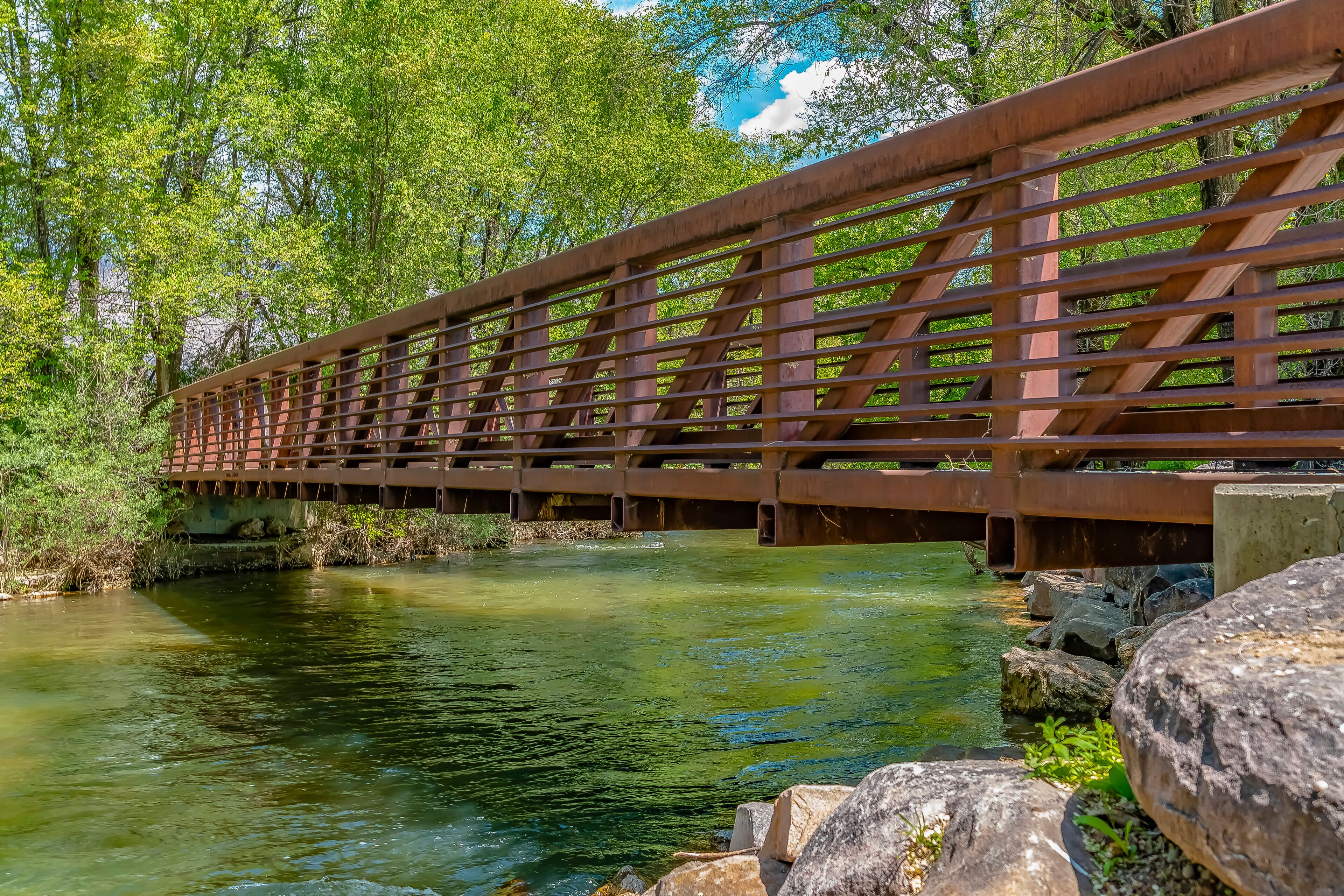 Bridge over glistening river with rocks on the bank at Ogden River Parkway