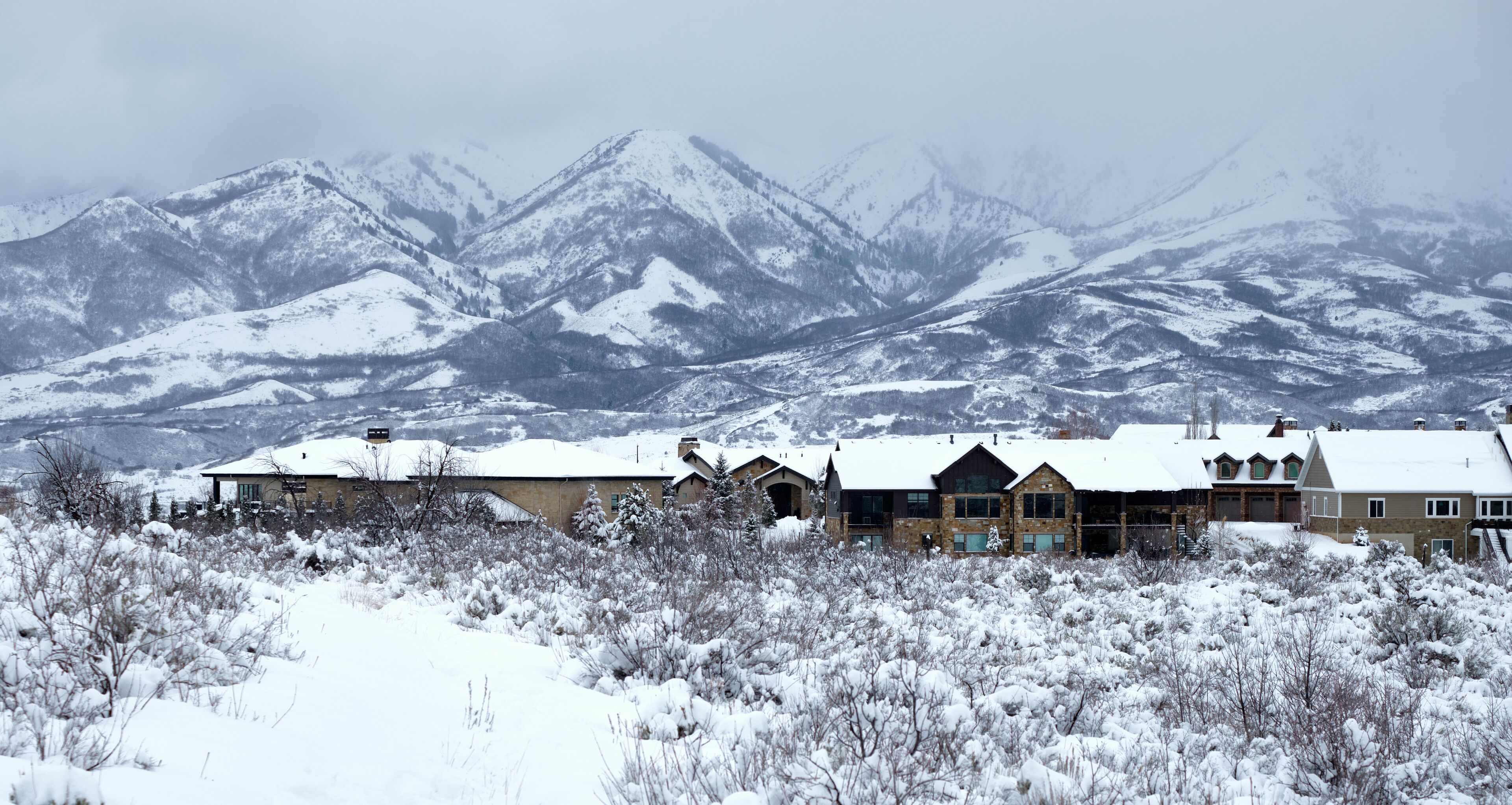 A snow-covered mountain range with a lodge in the foreground.