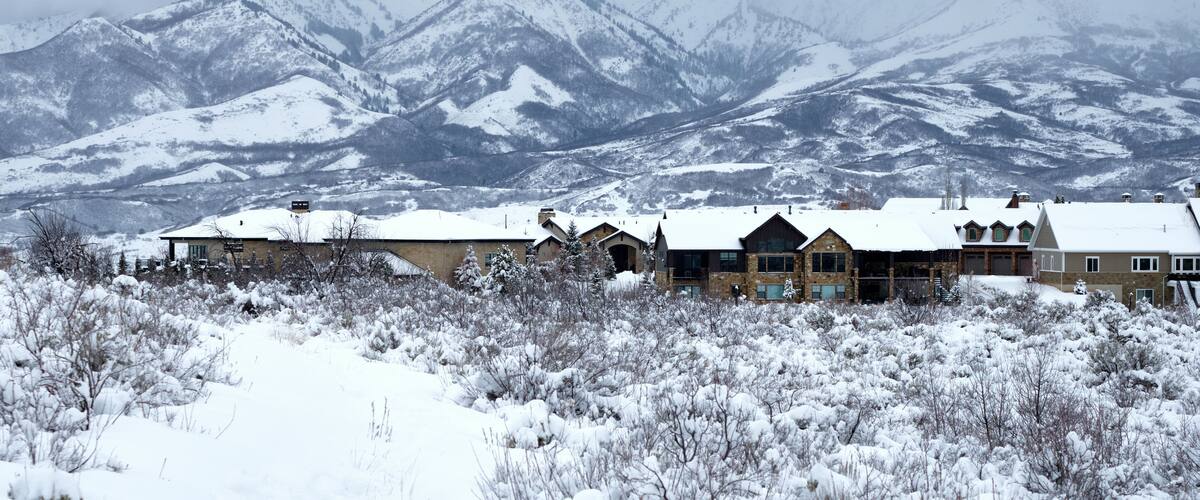 A snow-covered mountain range with a lodge in the foreground.