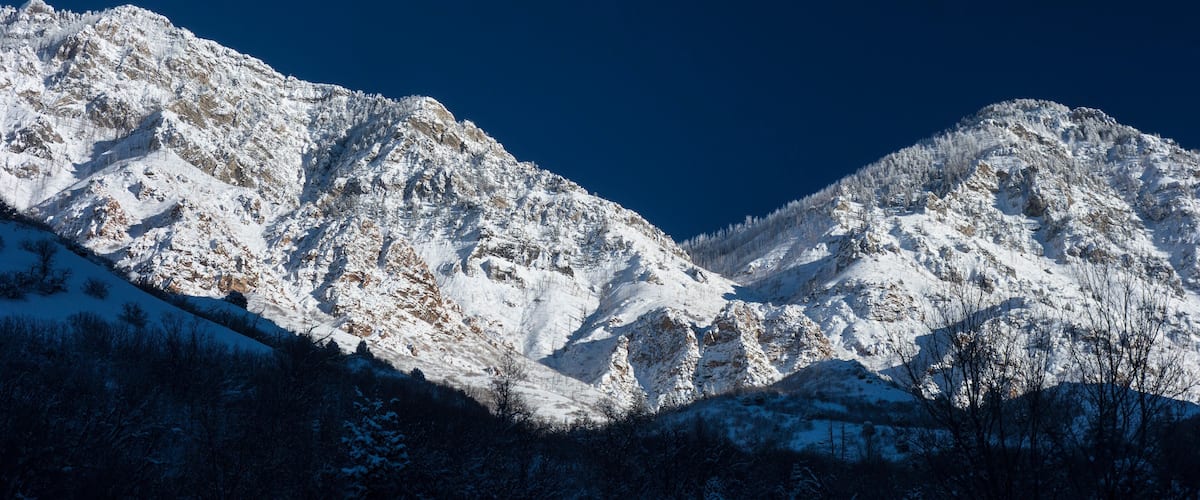 A snow-covered mountain range with a crescent moon in the sky.