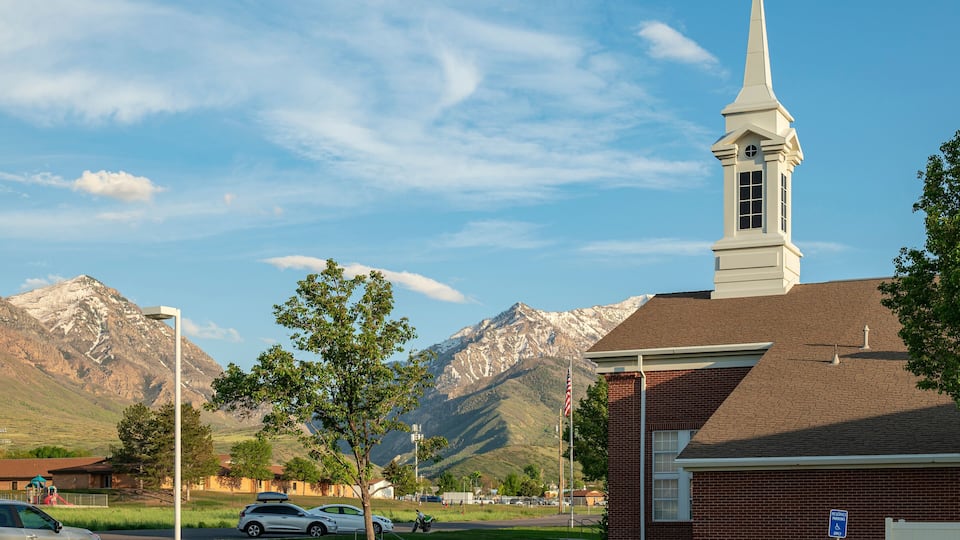 A church with a steeple, a mountain range, and a parking sign.