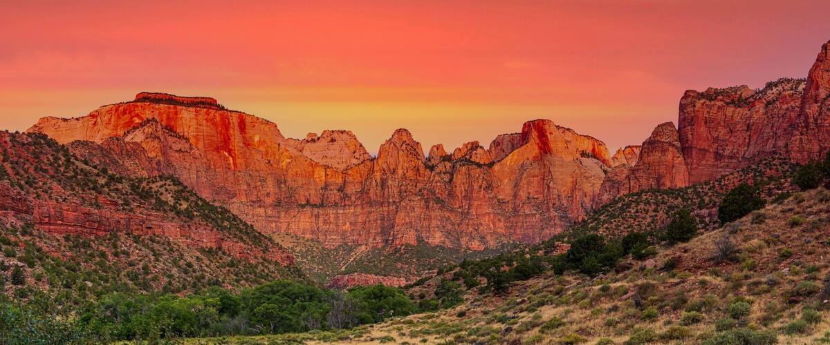A canyon with red rock formations and sparse vegetation.