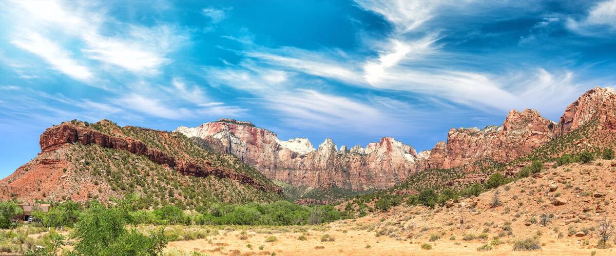 A desert landscape with red rock formations and sparse vegetation under a clear blue sky.