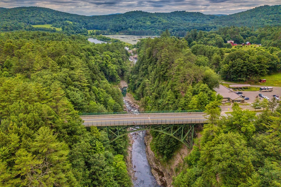 Un pont sobre un riu envoltat per una forest densa i turons.