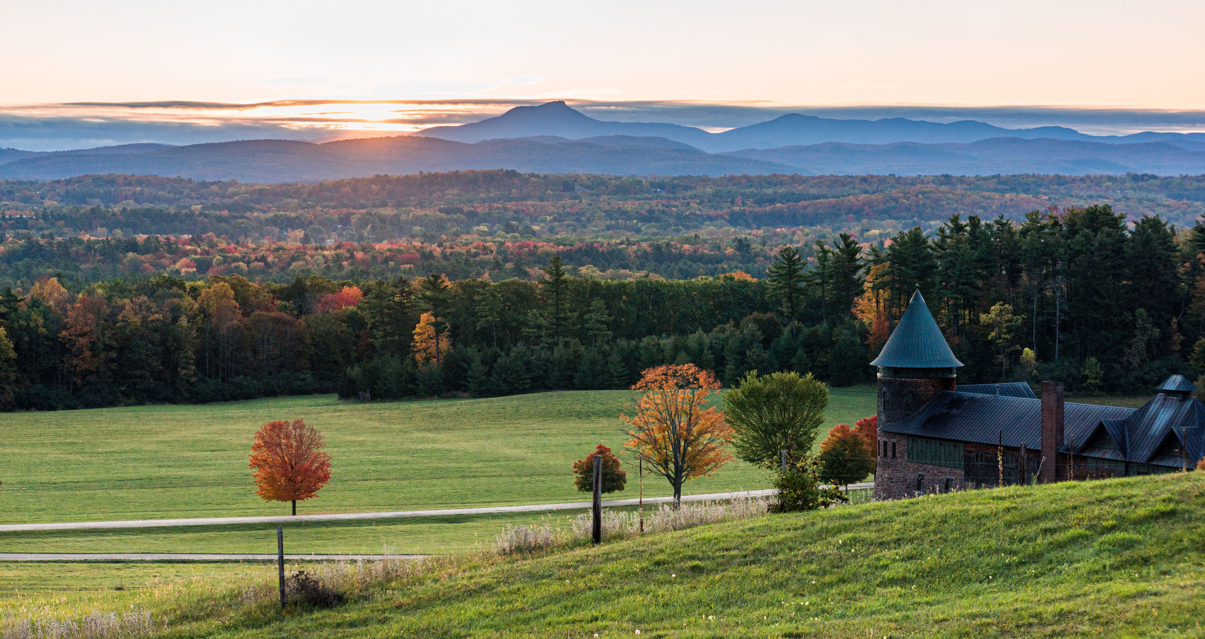 rising sun lights up  Camels Hump Mountain and the Champlain Valley  at Shelburne Farms  historic Barn