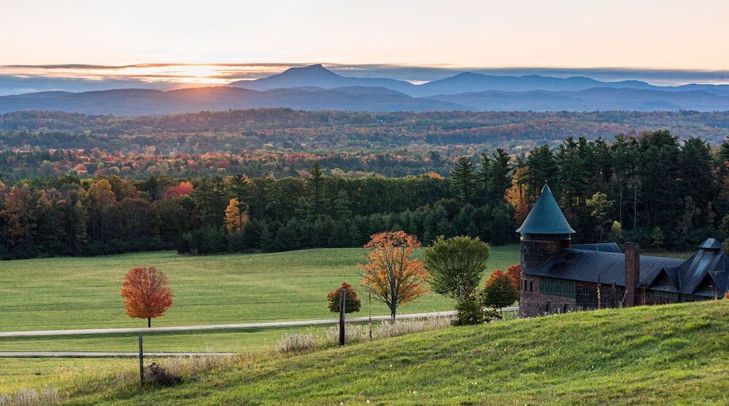 rising sun lights up Camels Hump Mountain and the Champlain Valley at Shelburne Farms historic Barn