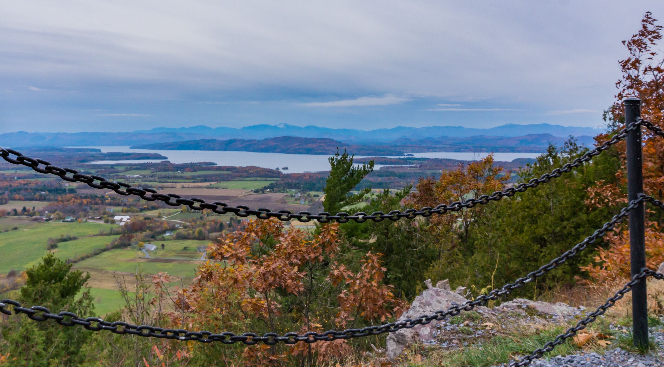 view from Mount Philo of rural Vermont farm valley in autumn  with Lake Champlain and the Adirondack Mountains  in distance 

