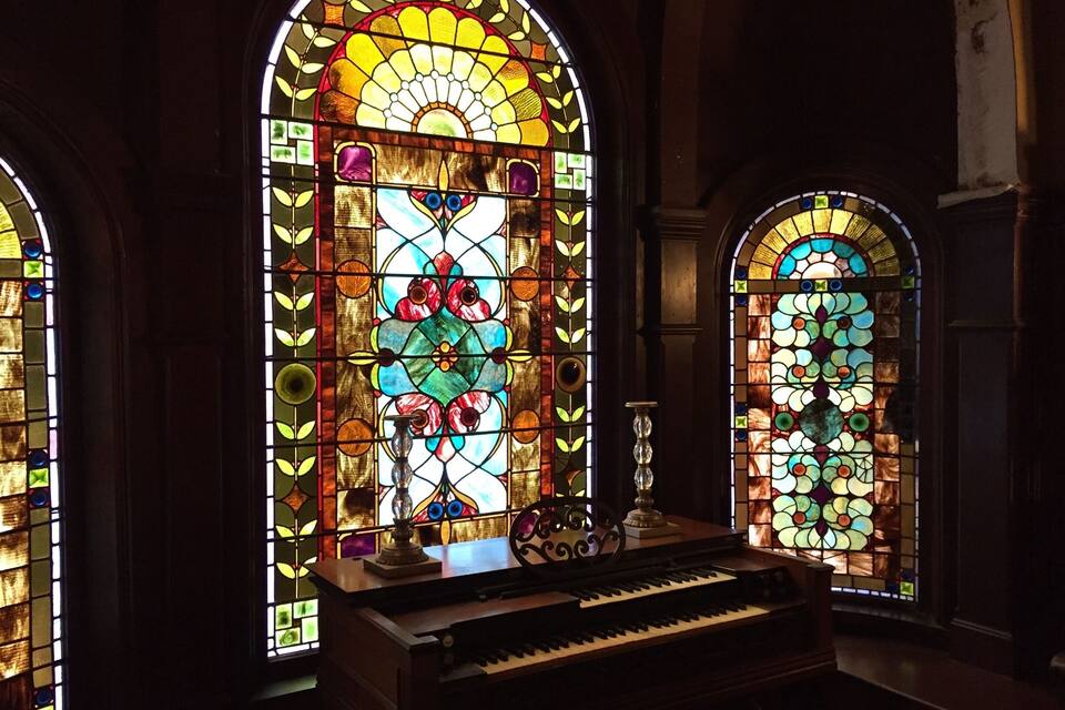 A church interior with stained glass windows and a piano.