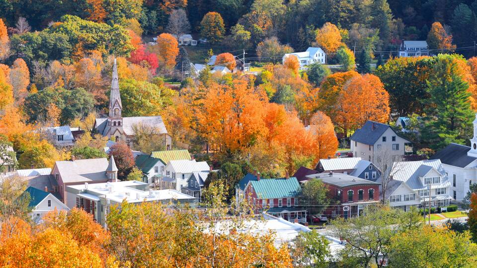 A town with autumn-colored trees, a church, and residential buildings.
