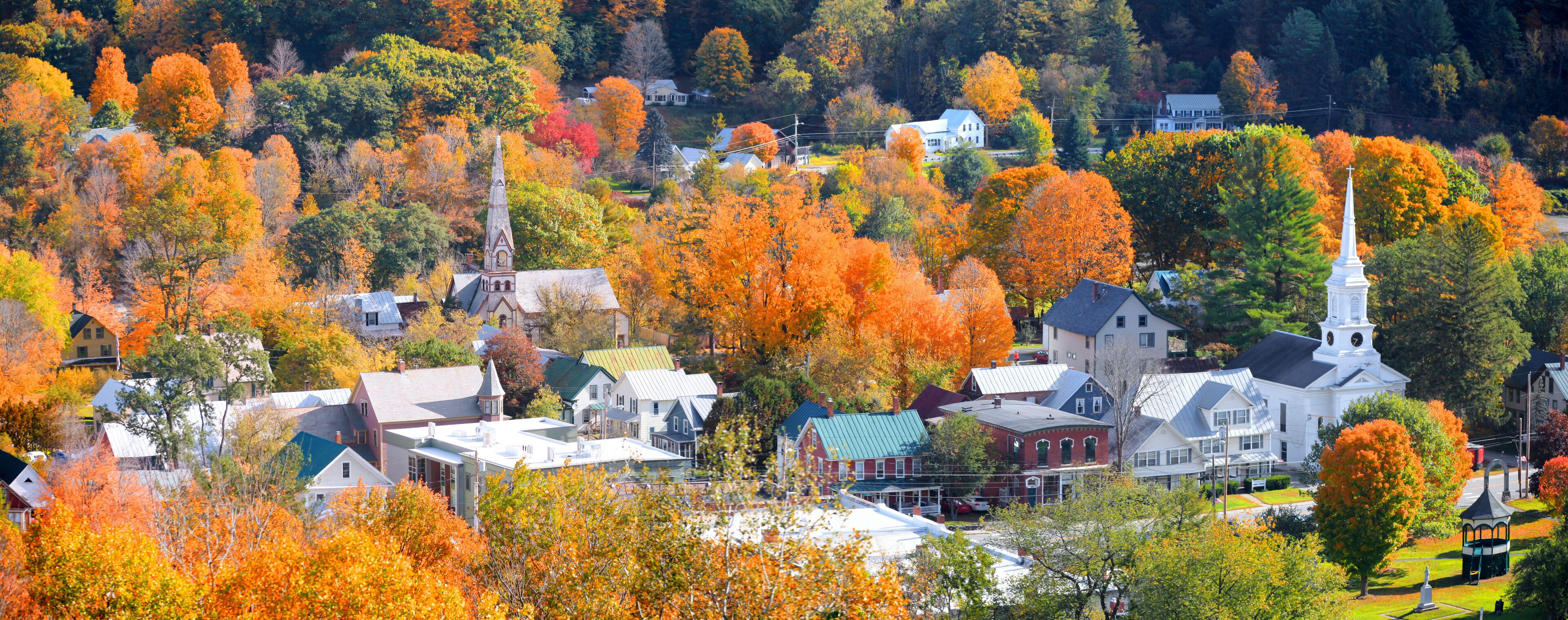 A town with autumn-colored trees, a church, and residential buildings.