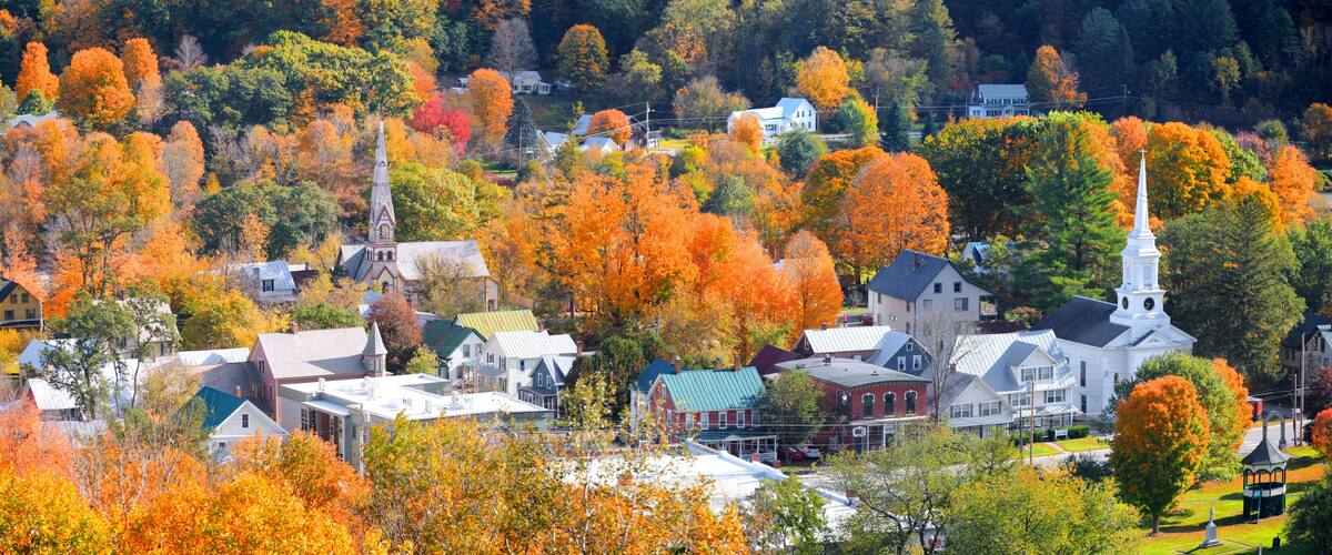 A town with autumn-colored trees, a church, and residential buildings.