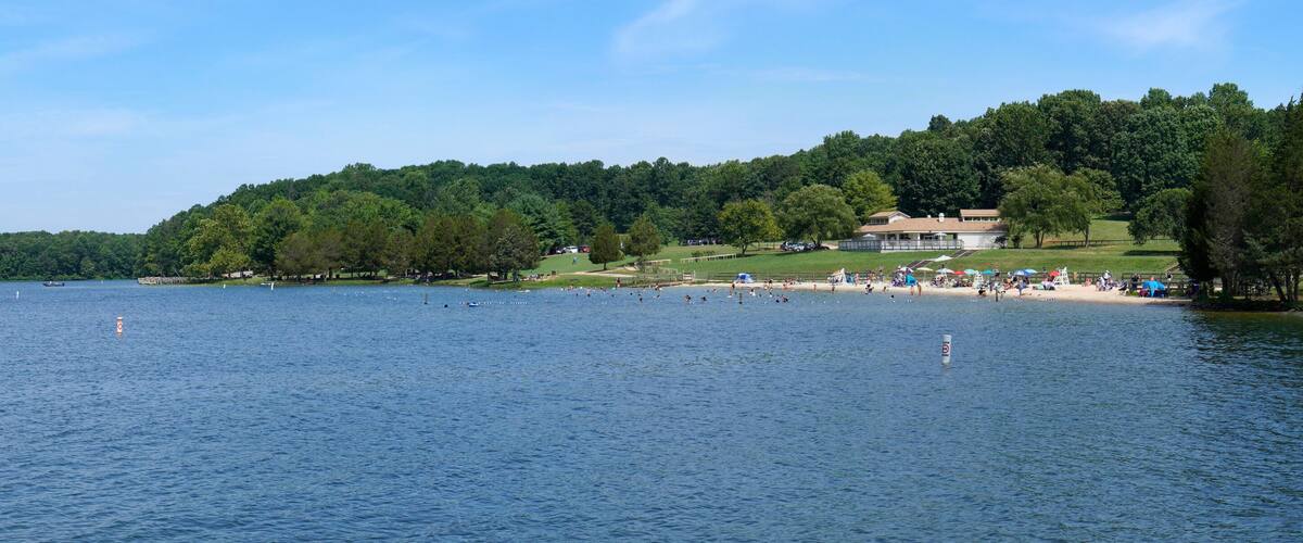 A lake with boats, a beach, and a forested hill.
