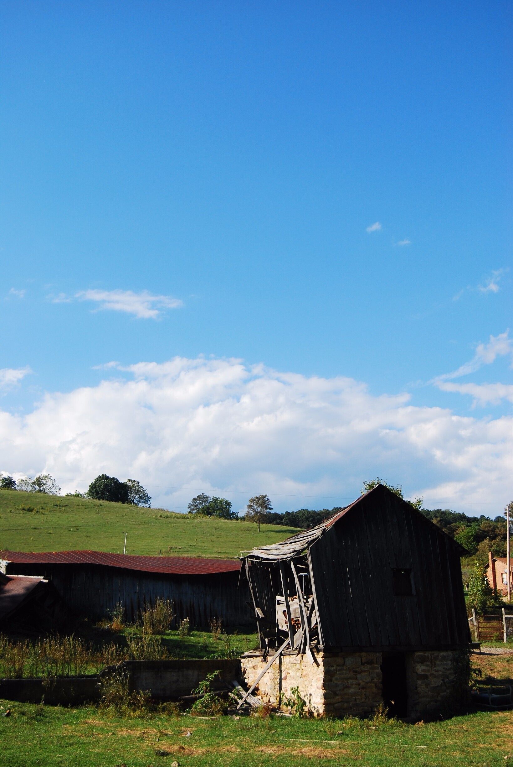 An old, dilapidated barn with a red roof in a rural setting.