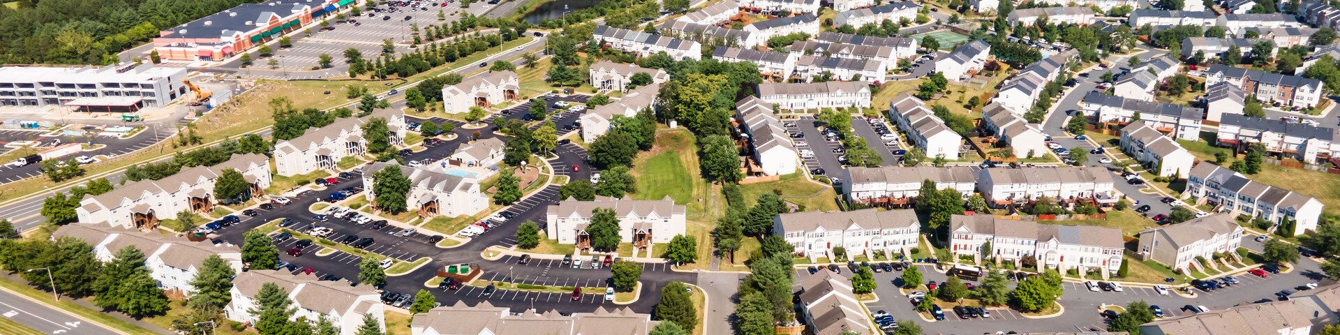 Vista aérea de uma área suburbana com casas residenciais, ruas e um grande reservatório de água.