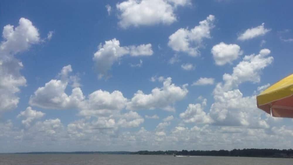 Ein Strand mit blauem Himmel, roten Strandbällen und einem gelben Sonnenschirm.