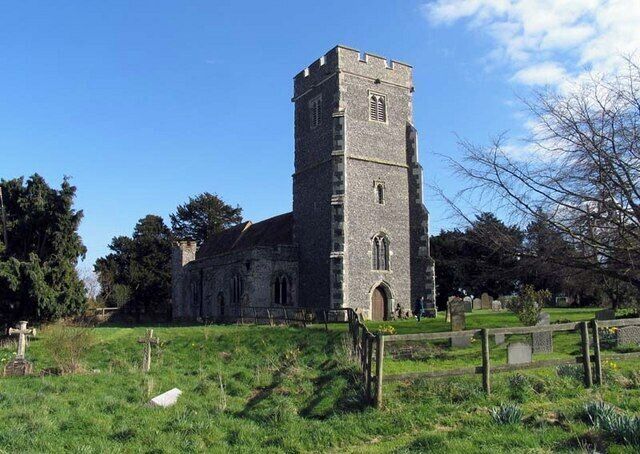 A historic church with a tall tower and a cemetery in the foreground.