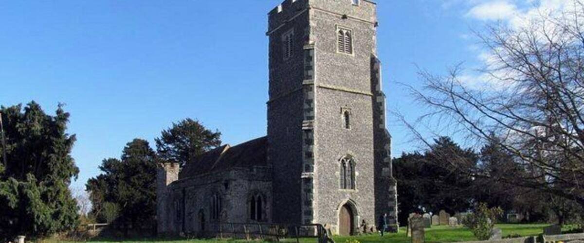 A historic church with a tall tower and a cemetery in the foreground.