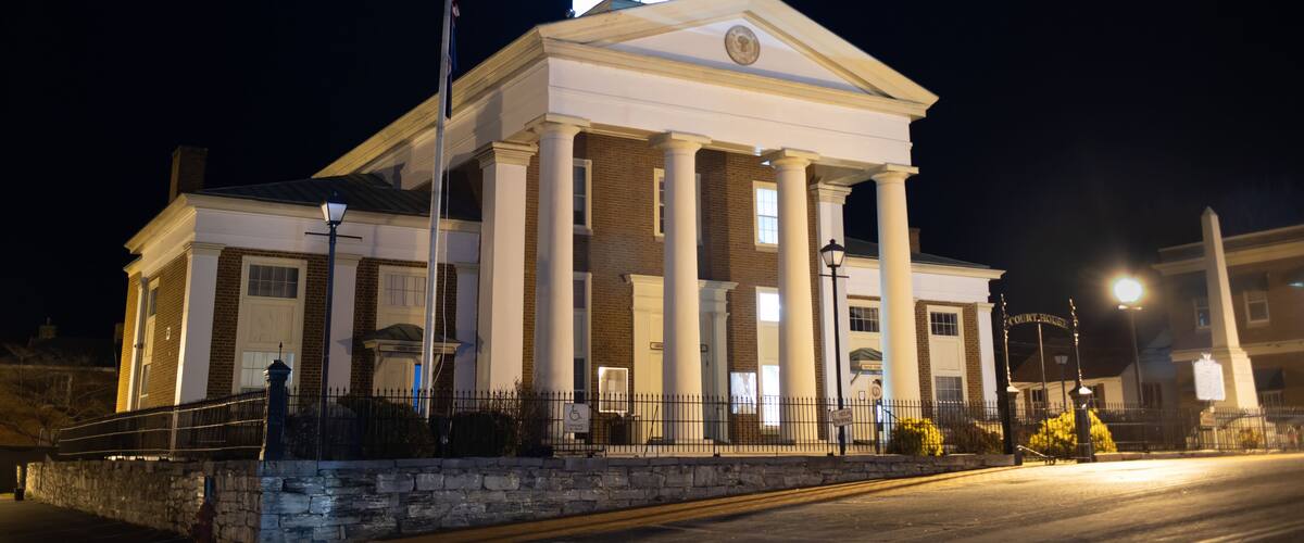 A historic building with a clock tower, columns, and a flagpole.