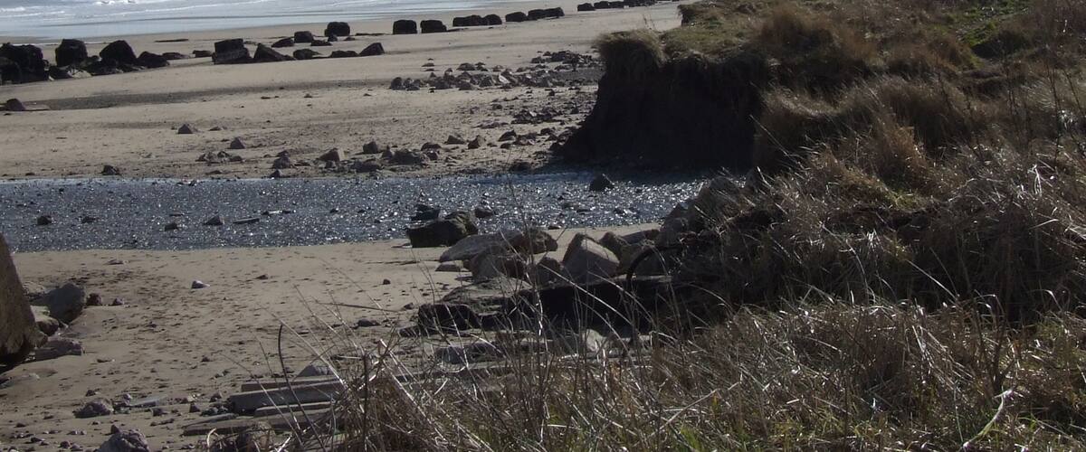 A rocky beach with waves crashing onto the shore and a clear sky.