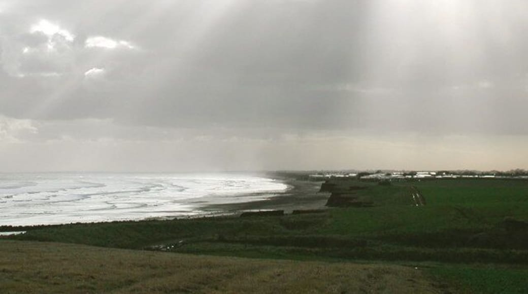 South Field, Barmston, East Riding of Yorkshire, England. Looking south across Barmston Drain towards Ullrome caravan park. There's an odd little bit of Barmston parish just south of here, where the parish boundary wanders out across the beach and back inland at 'Highlands' just north of the caravan park in the picture. Whatever feature caused the boundary to take this course has long ago been lost to coastal erosion.