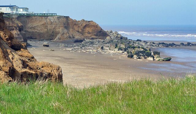 Clay cliffs and sea defences, Barmston, East Riding of Yorkshire, England. The rocks were put in place as part of the defences against invasion in the Second World War. As a consequence, the cliffs erode slightly slower behind the defences, and slightly faster on either side.
