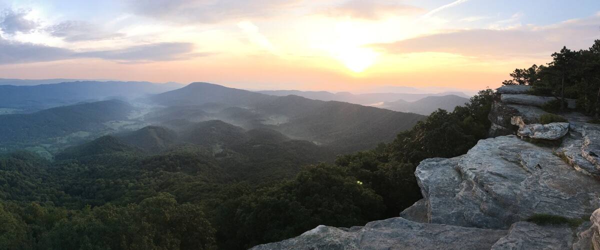 A mountainous landscape with dense forests and a clear sky.