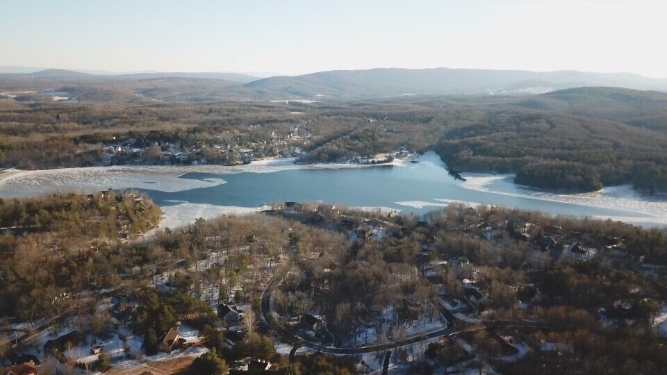 A lake surrounded by forested hills and a small town.