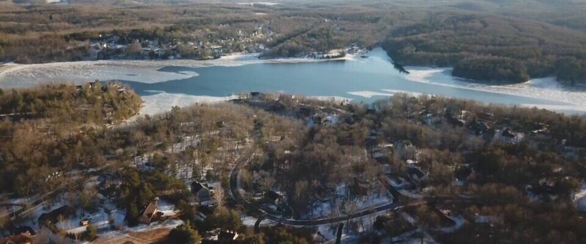 A lake surrounded by forested hills and a small town.
