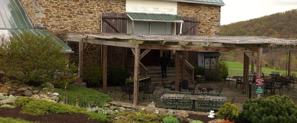 A stone building with a green roof and a covered patio area with outdoor seating.
