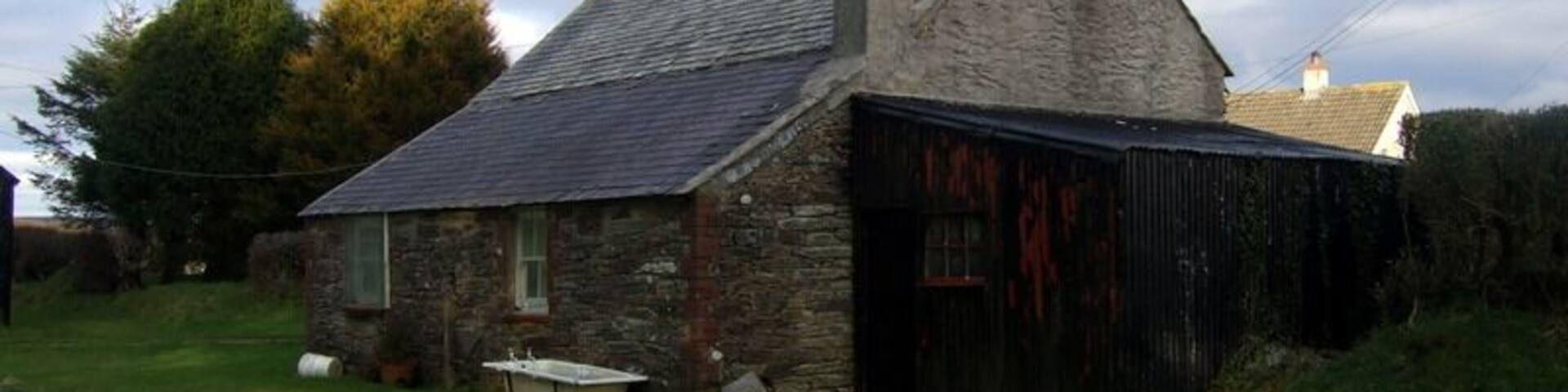 Rear of old cottage (1). A peep behind 1711846 reveals that its traditional appearance is equally perfect there too. The single-storey extension at the rear is typical and so is the corrugated iron lean-to. The old bath provides the finishing touch!