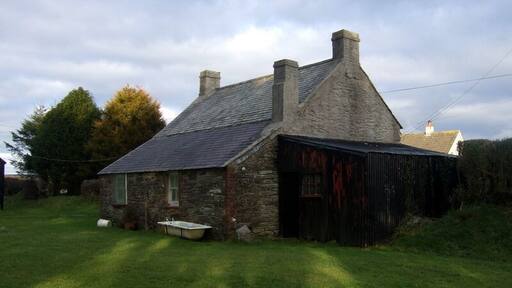 Rear of old cottage (1). A peep behind 1711846 reveals that its traditional appearance is equally perfect there too. The single-storey extension at the rear is typical and so is the corrugated iron lean-to. The old bath provides the finishing touch!
