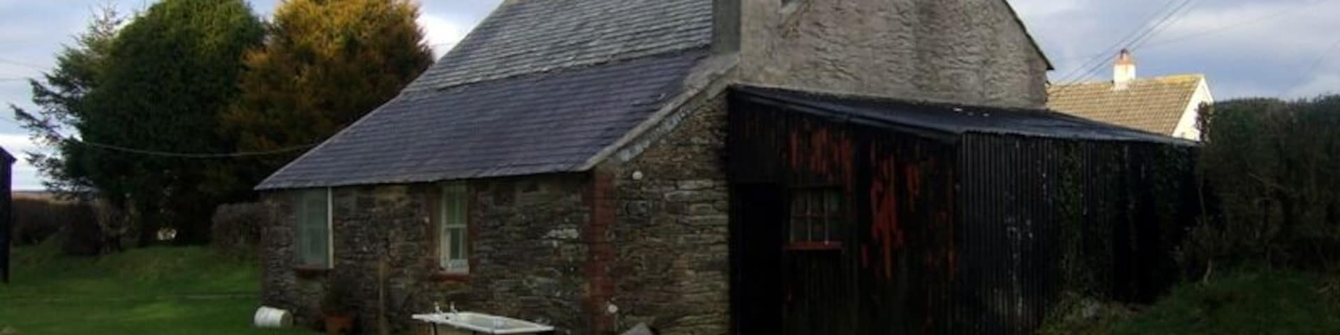 Rear of old cottage (1). A peep behind 1711846 reveals that its traditional appearance is equally perfect there too. The single-storey extension at the rear is typical and so is the corrugated iron lean-to. The old bath provides the finishing touch!