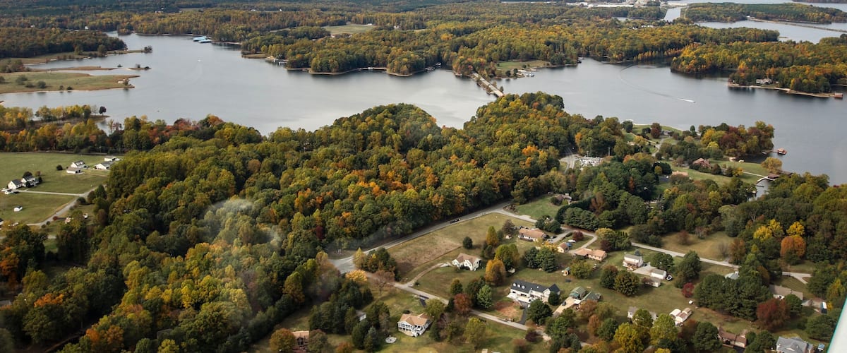 A lake surrounded by dense forests and scattered houses.