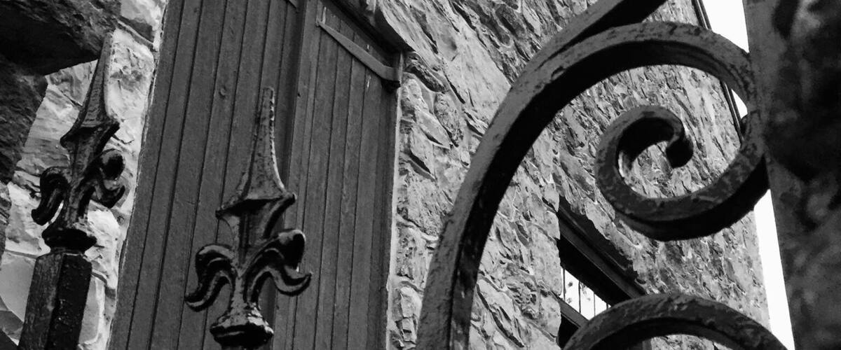 A stone building with a wooden door and decorative ironwork.