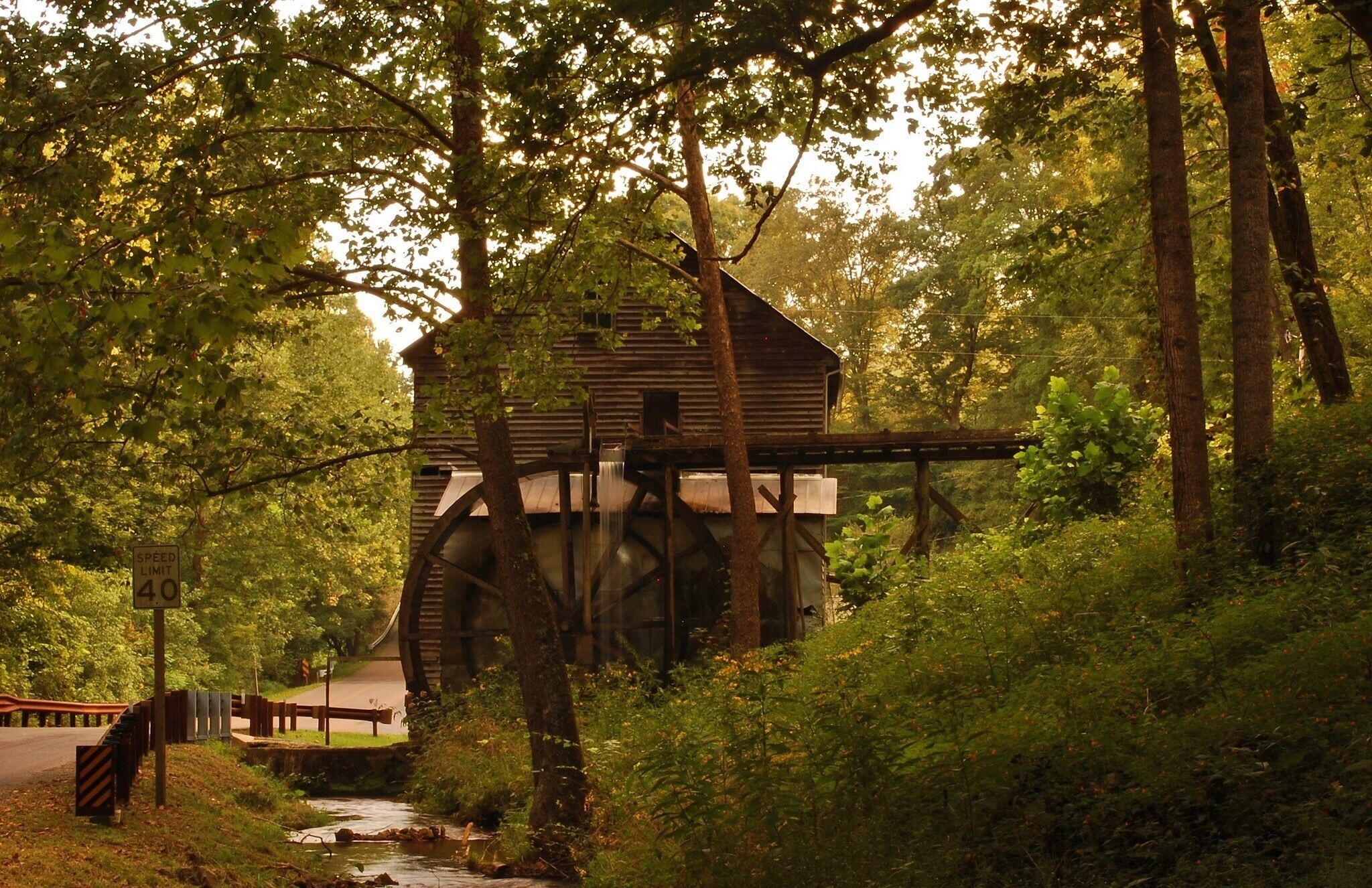 A watermill in a forested area with a speed limit sign of 40.