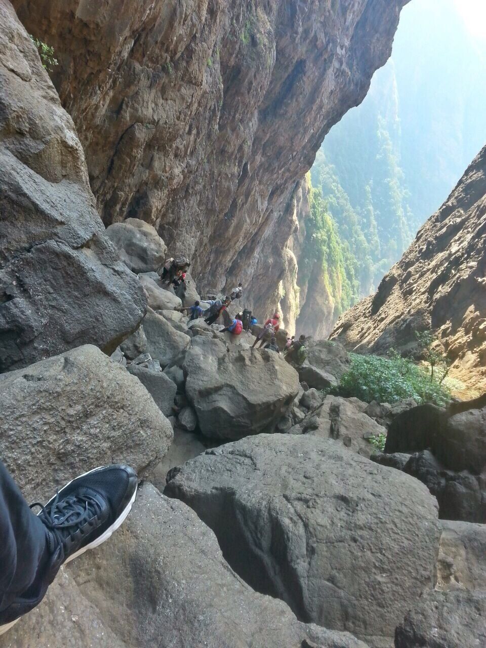 A rocky canyon with hikers climbing a steep rock face.