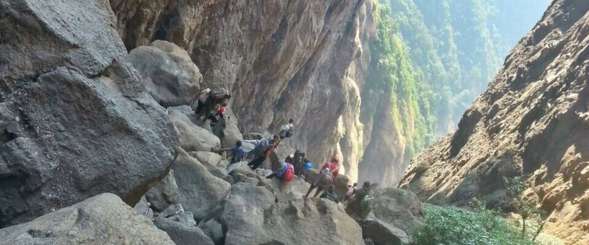 A rocky canyon with hikers climbing a steep rock face.