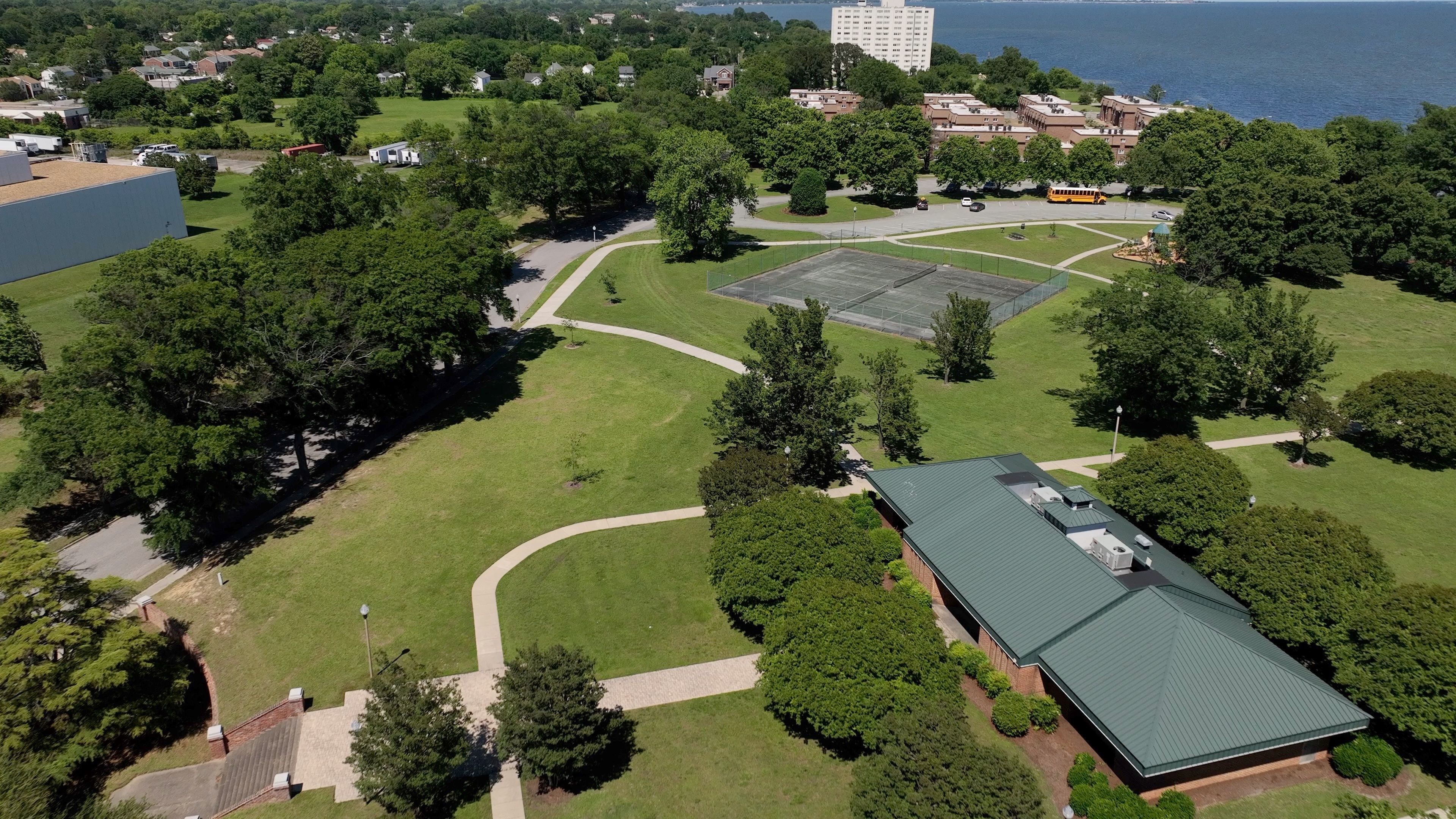 An aerial view of a campus with green lawns, pathways, a sports field, and buildings.
