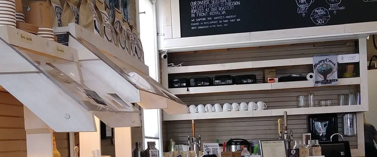 A coffee shop interior with a wooden counter, coffee machines, and a chalkboard menu.