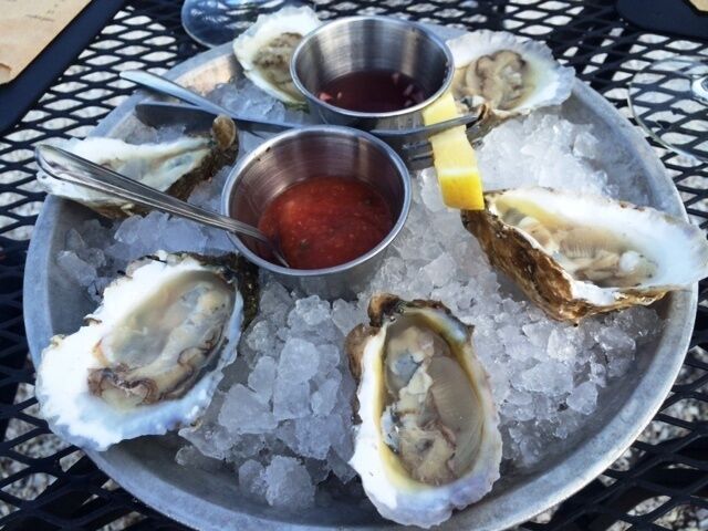 A plate of oysters on ice with two dipping sauces.