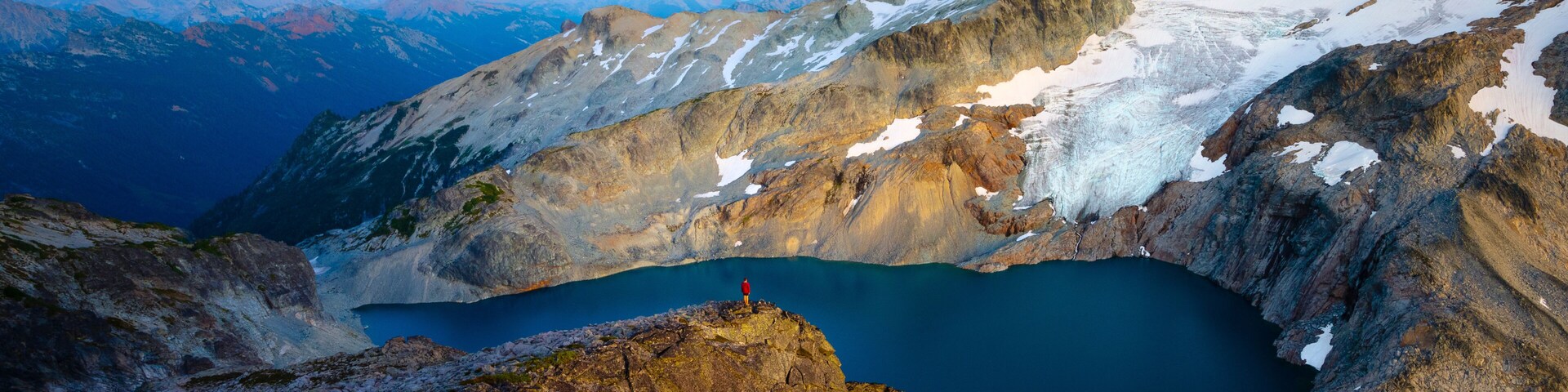 Un paisaje montañoso con un glaciar, un lago y una luna en el cielo.