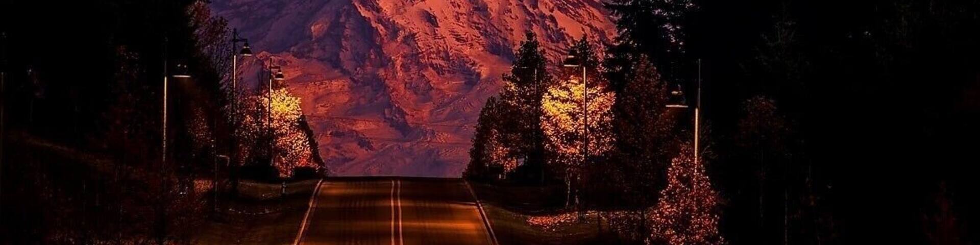 A road leading to a snow-capped mountain at dusk.