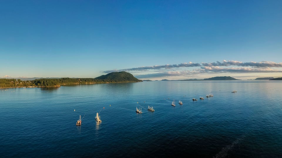 A coastal town with a calm sea, boats, and a distant mountain range.