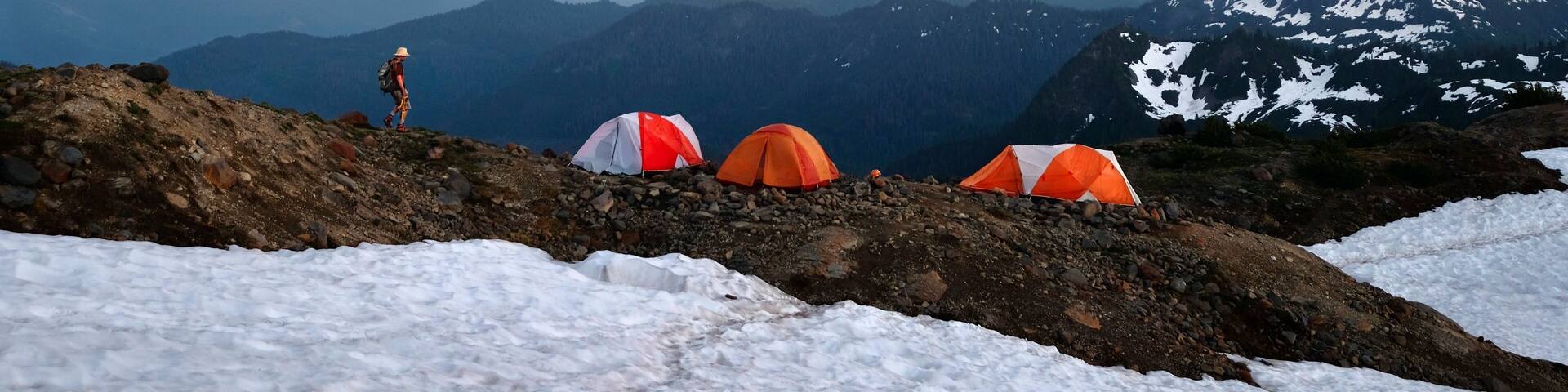 Man walking on ridge to his tent on base camp on Easton Glacier. Mount Baker. Washington. United States of America
