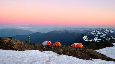 Man walking on ridge to his tent on base camp on Easton Glacier. Mount Baker. Washington. United States of America