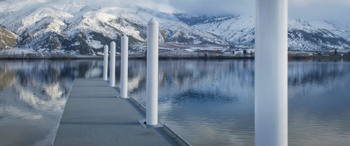 Pillars on dock at lake near snow covered mountain range